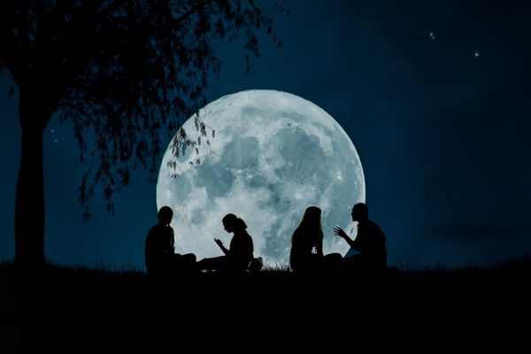 pessoas conversando com uma lua cheia atrás
